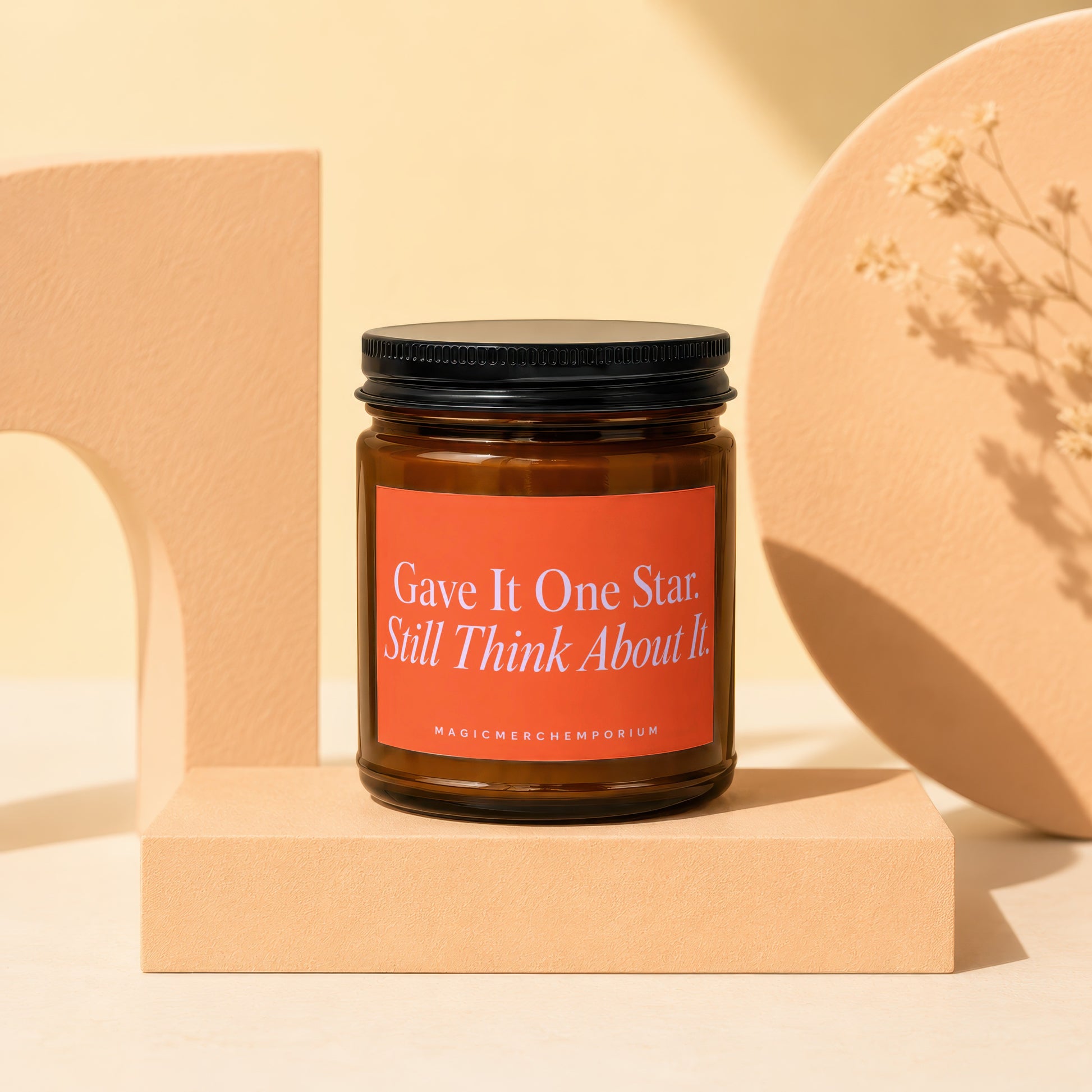 Amber jar candle with black lid and an orange label reading "Gave It One Star. Still Think About It."