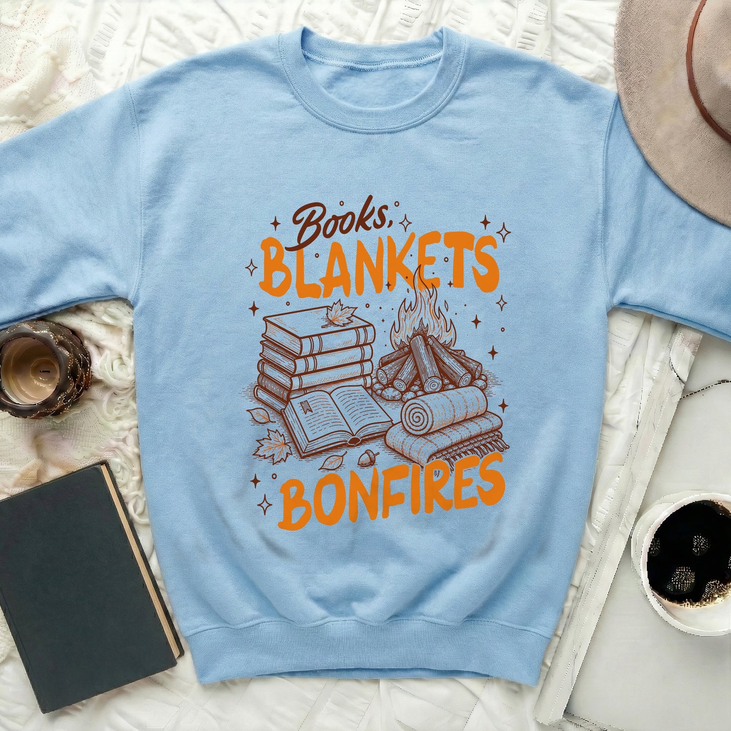 Light blue sweatshirt with "Books, Blankets, Bonfires" graphic and related illustrations.