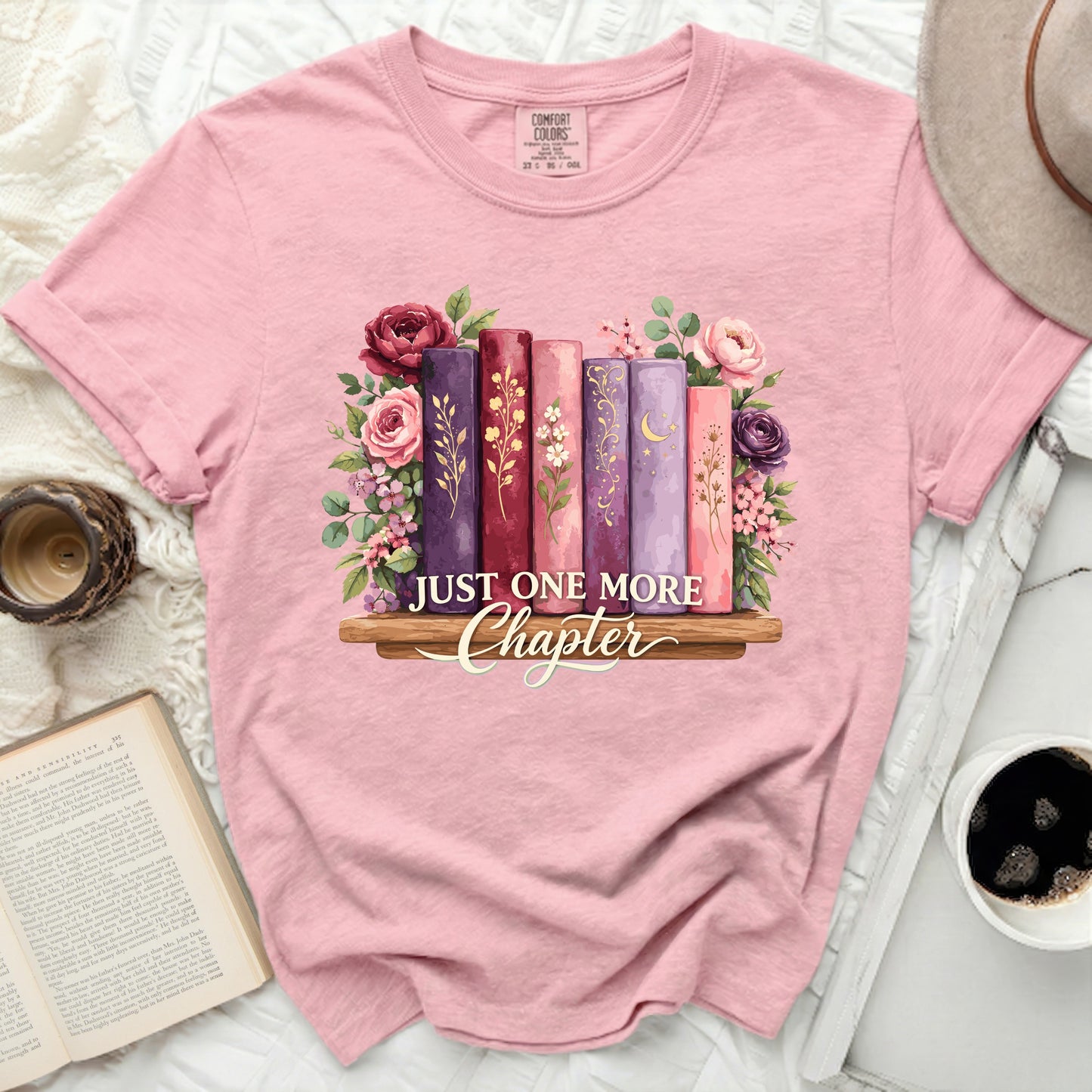 Pink t-shirt with "Just One More Chapter" and floral book graphic.