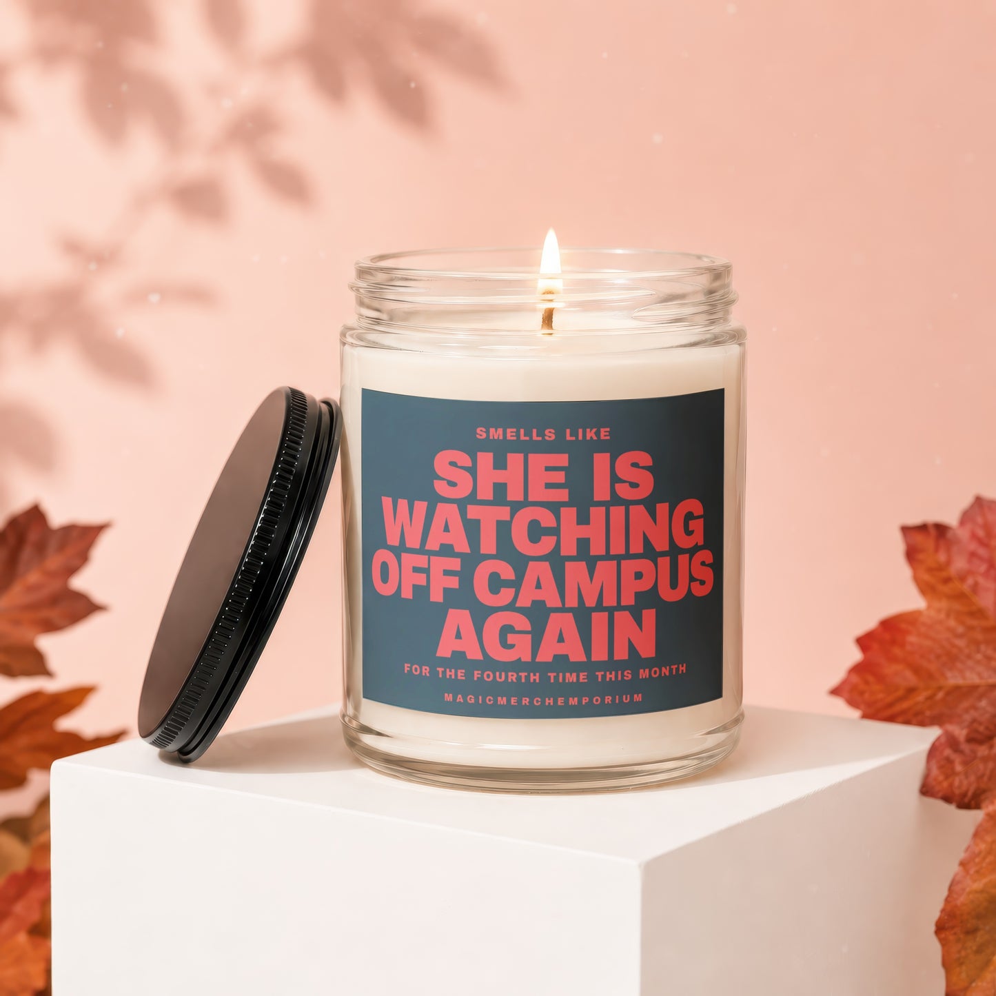 Candle with label "She is watching off campus again" with autumn leaves.