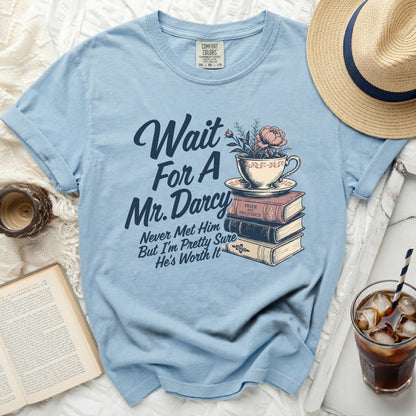 Light blue t-shirt with "Wait for a Mr. Darcy" and stack of books graphic.