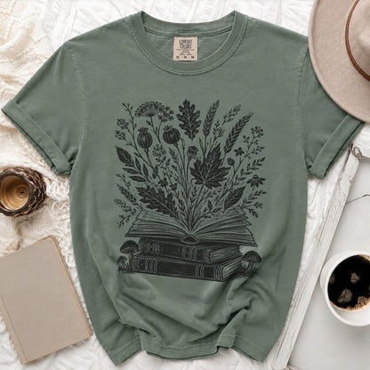 T-shirt with black graphic of open book overflowing with botanical illustrations.