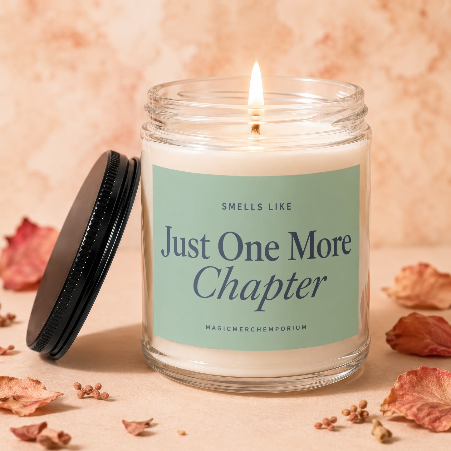 Jar candle reading "Just One More Chapter" surrounded by dried leaves and seeds.