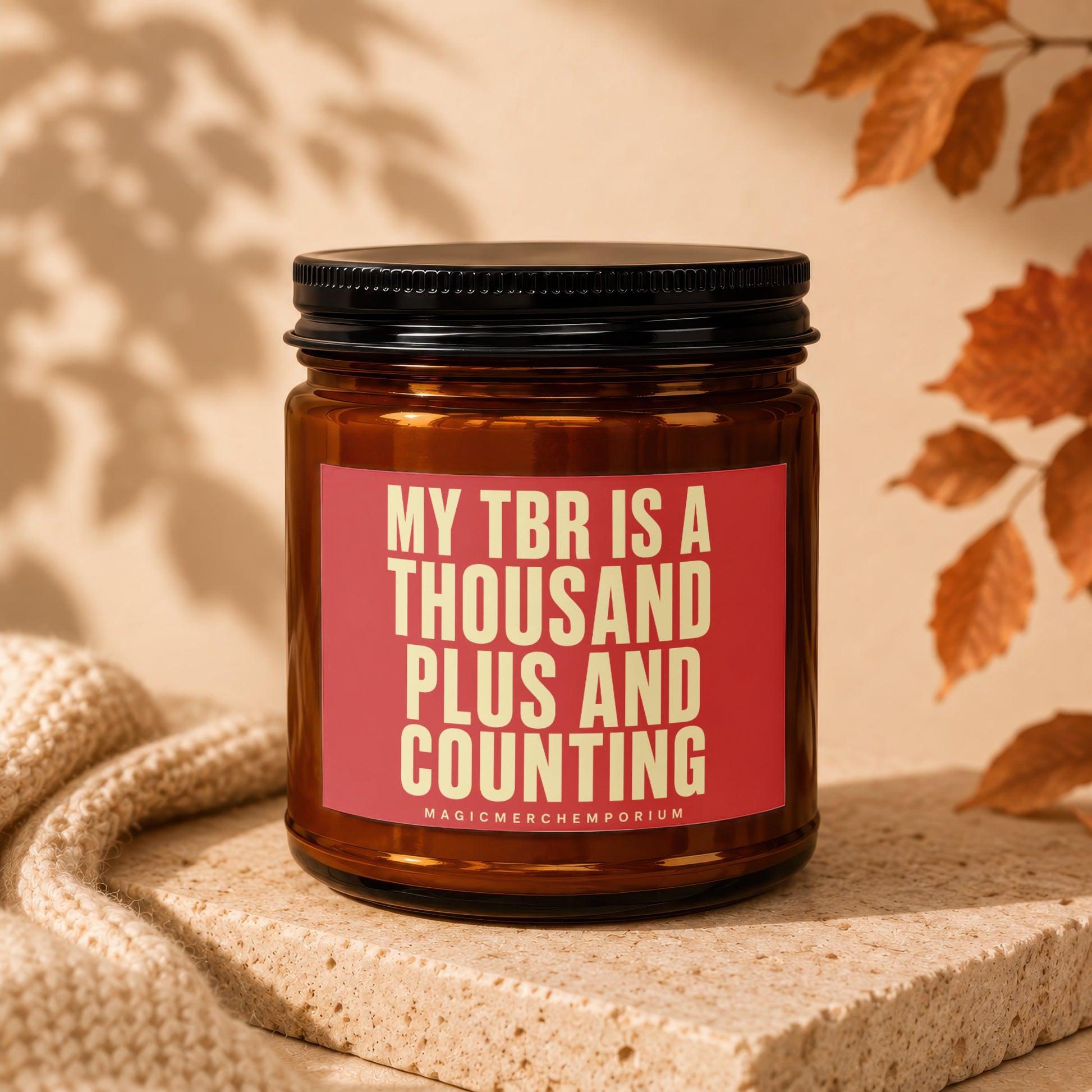 Amber jar candle with red label reading "MY TBR IS A THOUSAND PLUS AND COUNTING".