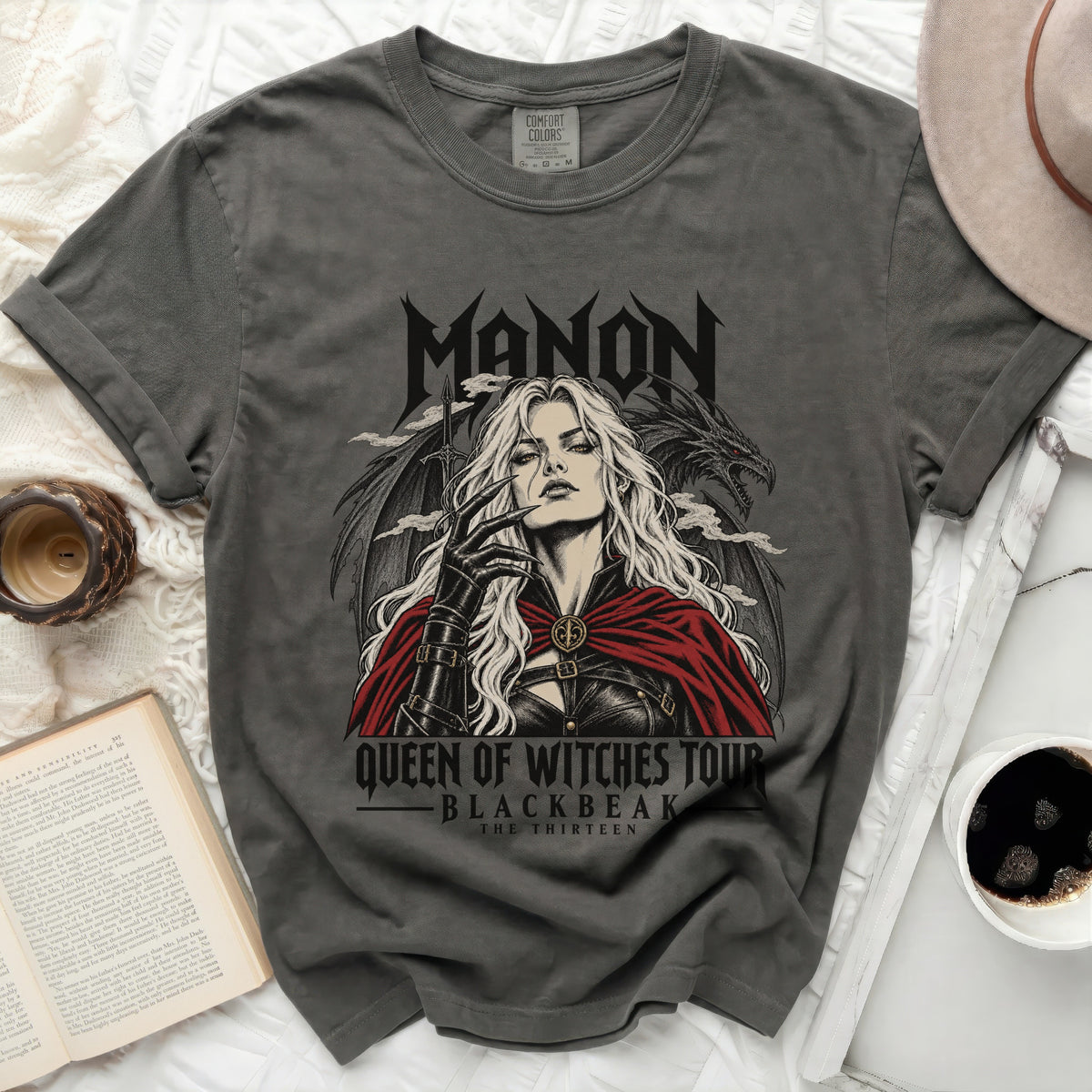 Grey t-shirt with "Manon Queen of Witches Tour Blackbeak The Thirteen" graphics.