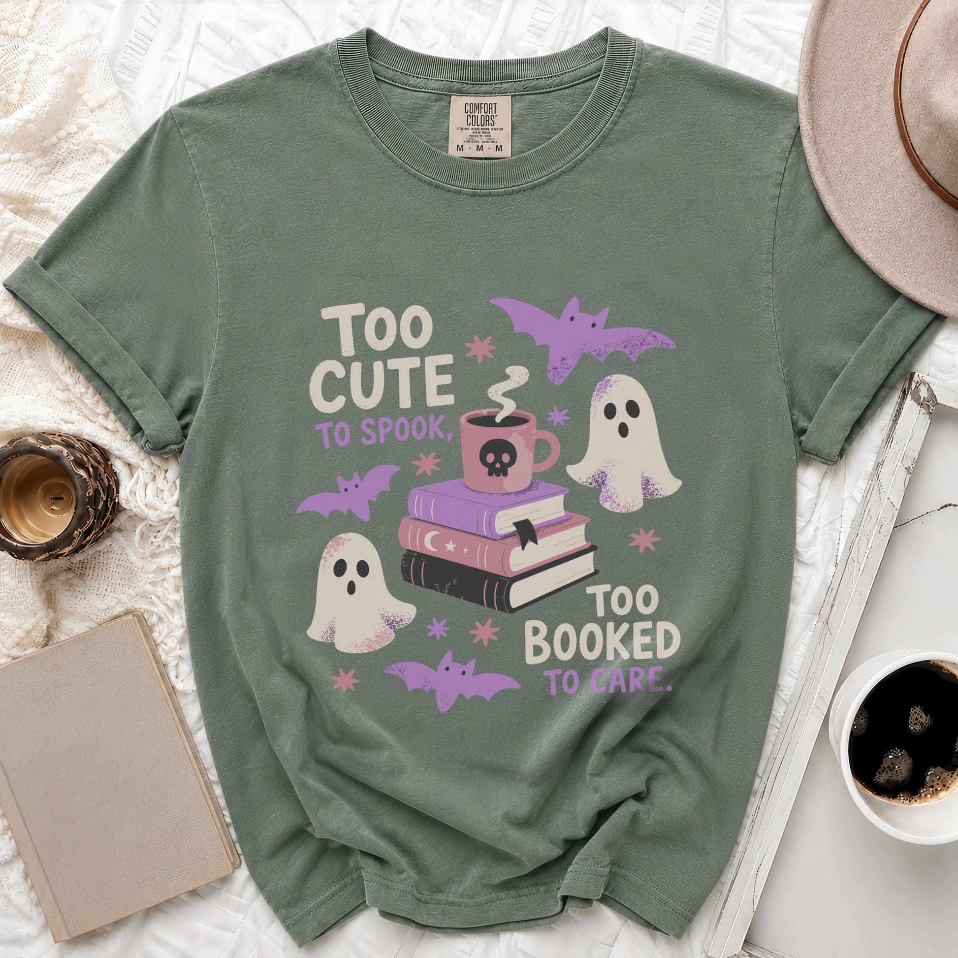 Green t-shirt with "Too cute to spook, too booked to care" text and Halloween graphics.