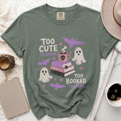 Green t-shirt with "Too cute to spook, too booked to care" text and Halloween graphics.