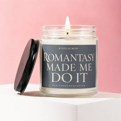 Lit glass candle with a black lid and label that reads "ROMANTASY MADE ME DO IT".