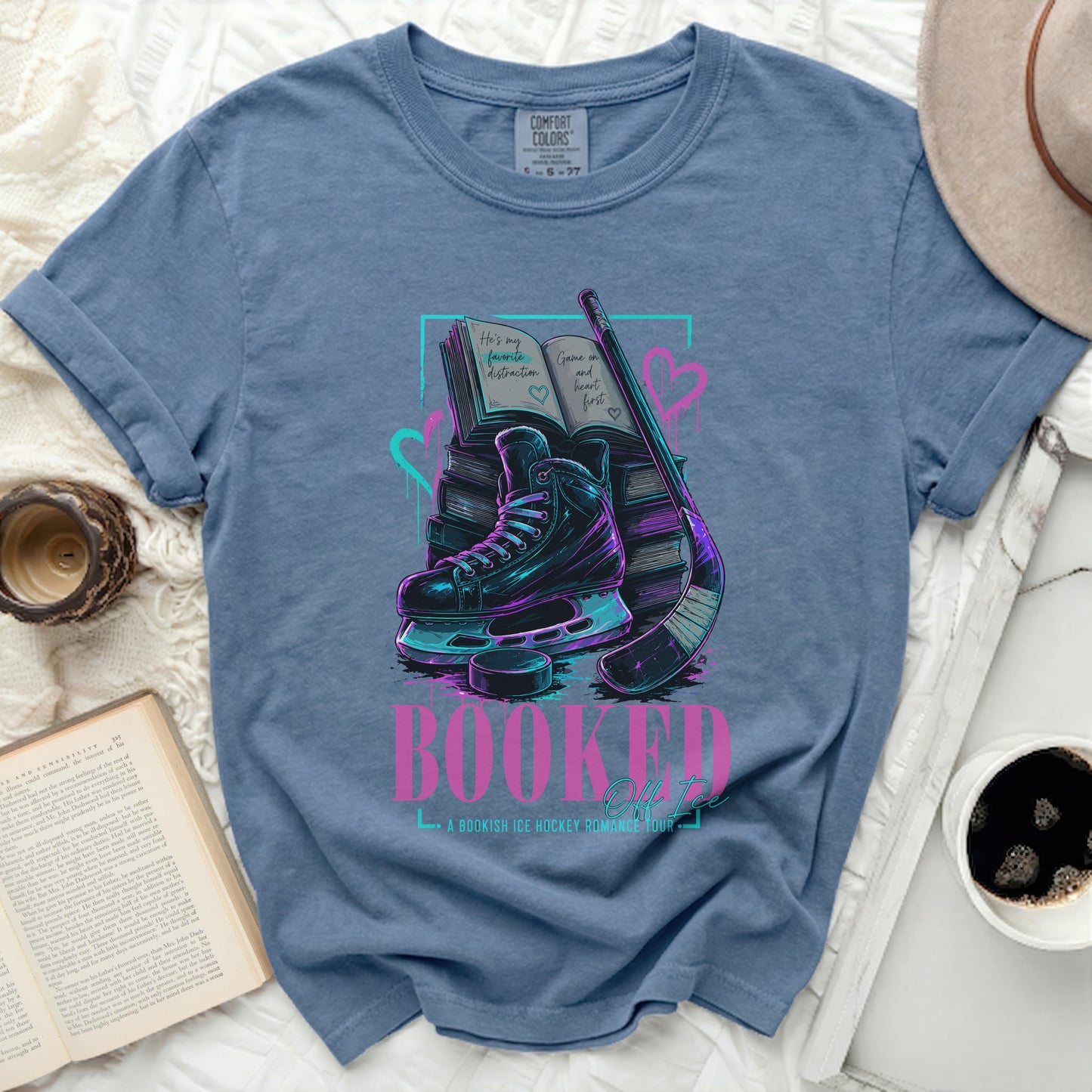 Blue t-shirt with ice skates, hockey stick, and book graphic.