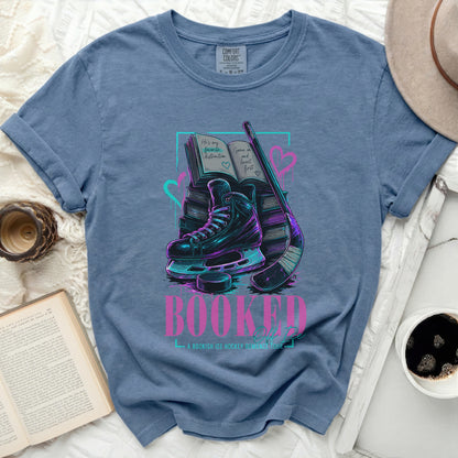 Blue t-shirt with ice skates, hockey stick, and book graphic.