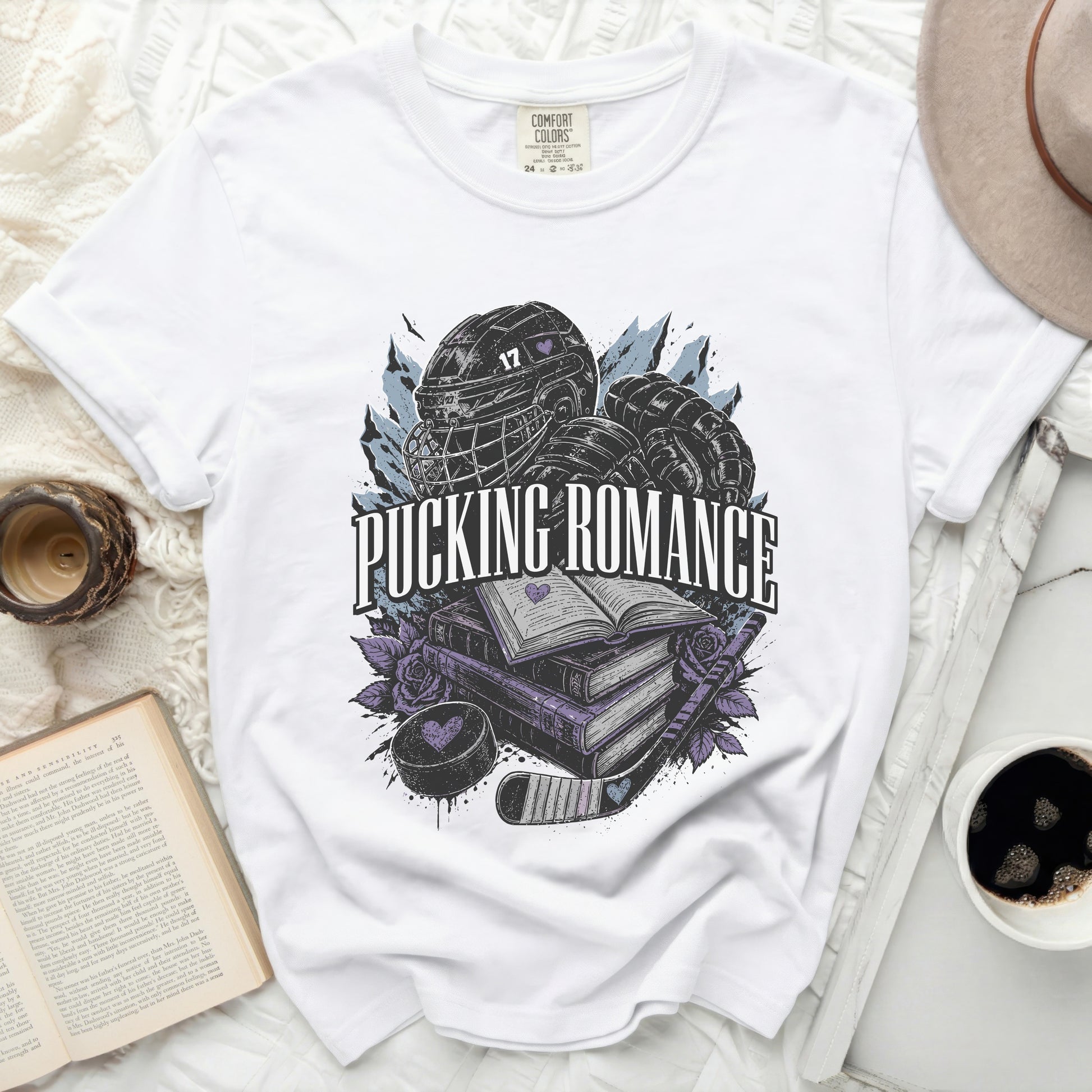White t-shirt with hockey puck, stick, helmet, and open books graphic