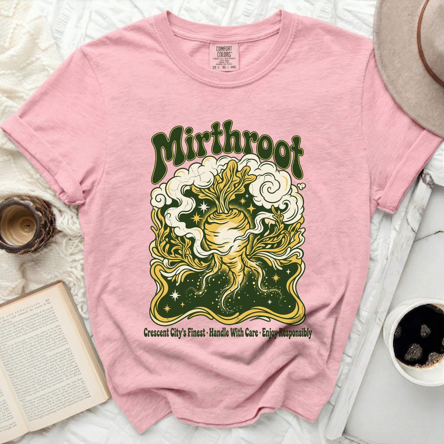 Pink t-shirt with "Mirthroot" and vegetable illustration, "Crescent City's Finest" text.