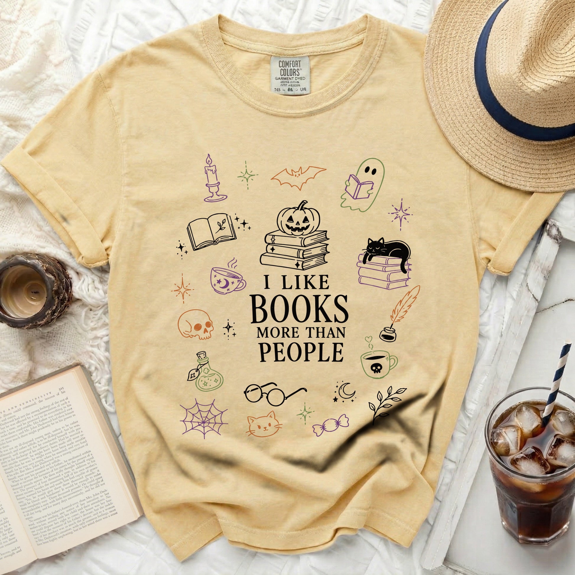 Yellow t-shirt with "I Like Books More Than People" and illustrated books, pumpkin, ghost, cat.