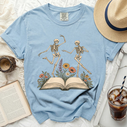 Two skeletons dancing on an open book with flowers.