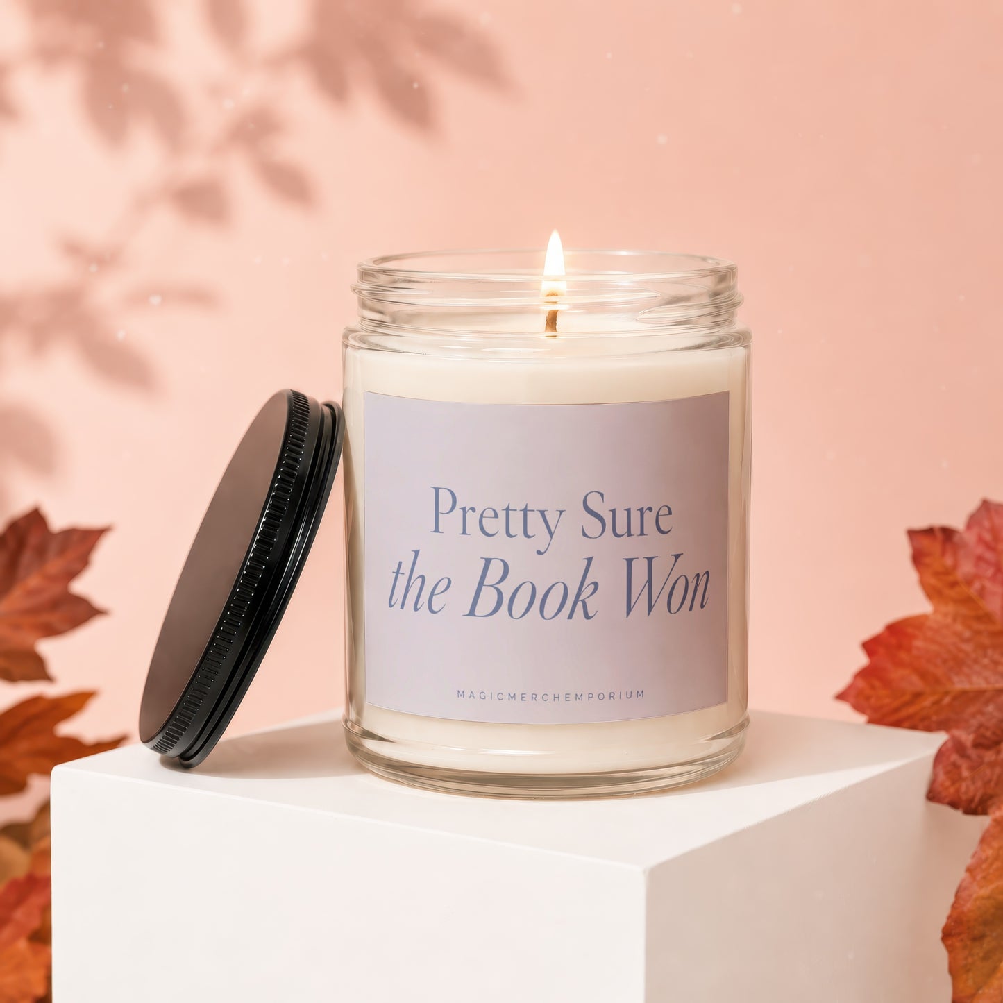 Candle with text "Pretty Sure the Book Won" and "MagicMerchEmporium" on label.