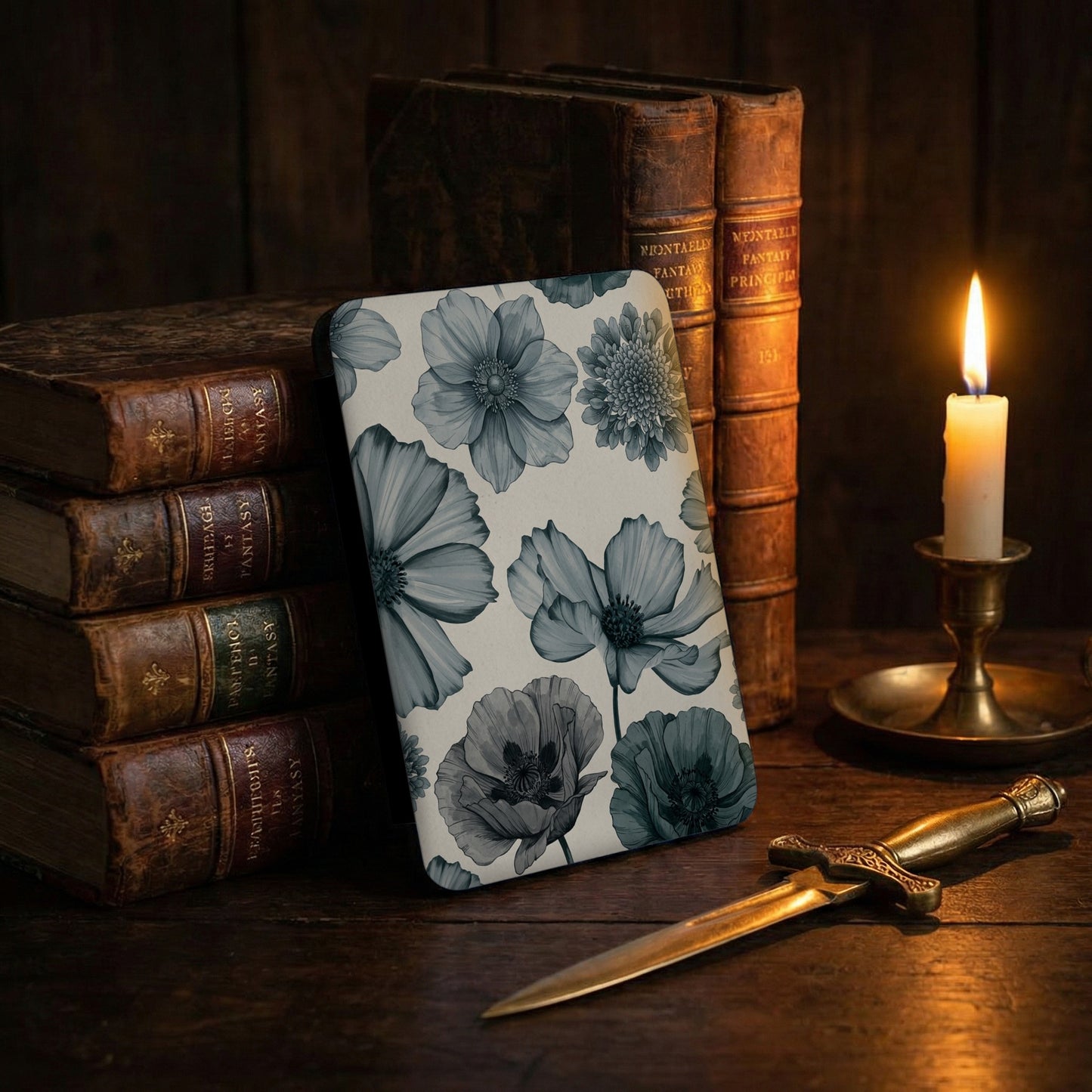 Book cover with a digital watercolor floral pattern beside old books and a candle.