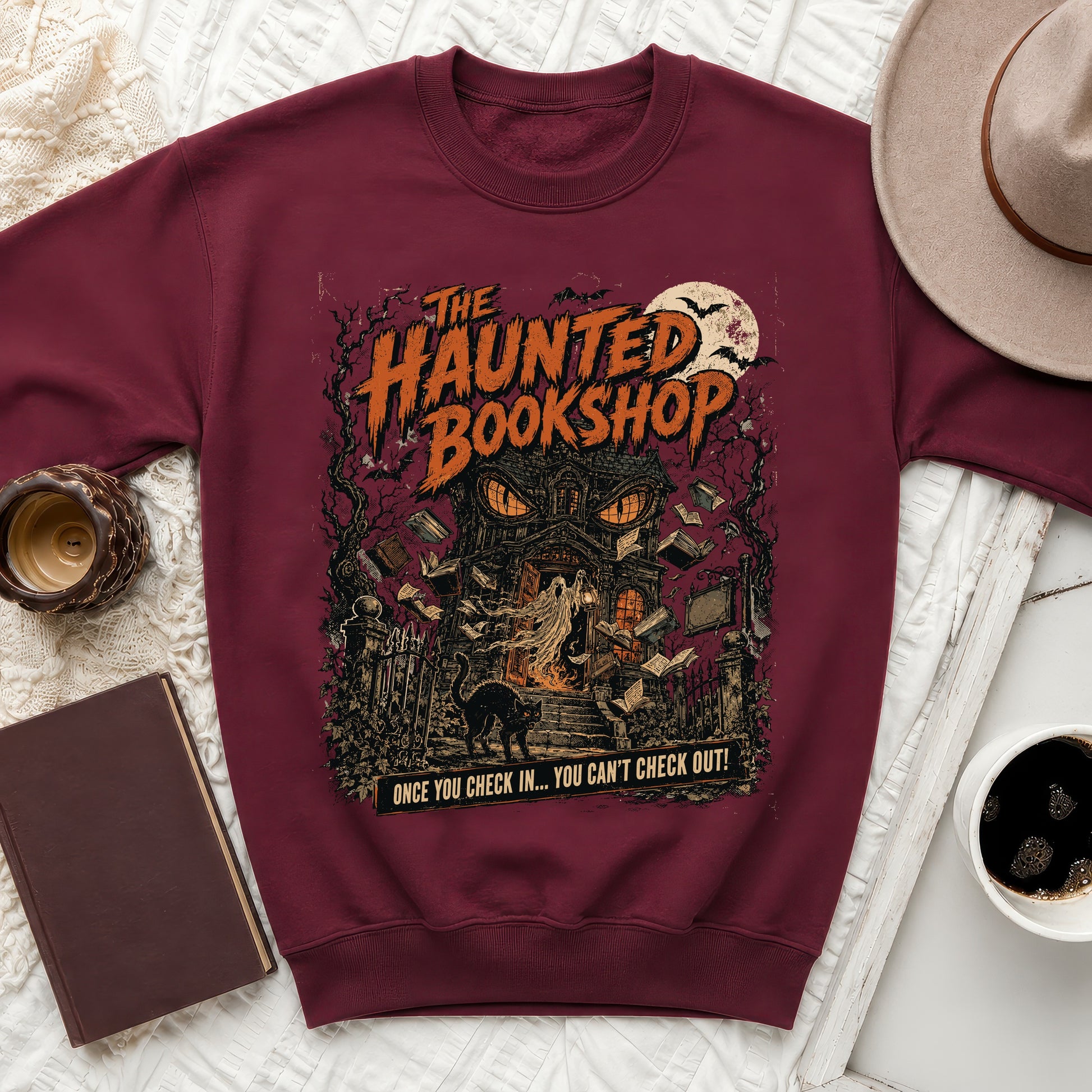 Maroon sweatshirt with "The Haunted Bookshop" graphic and ghost, black cat, and books.