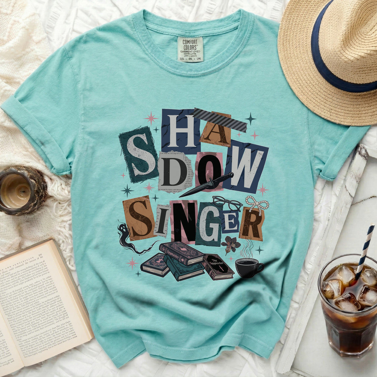 Teal t-shirt with "Shadow Singer" collage graphic and book illustrations.