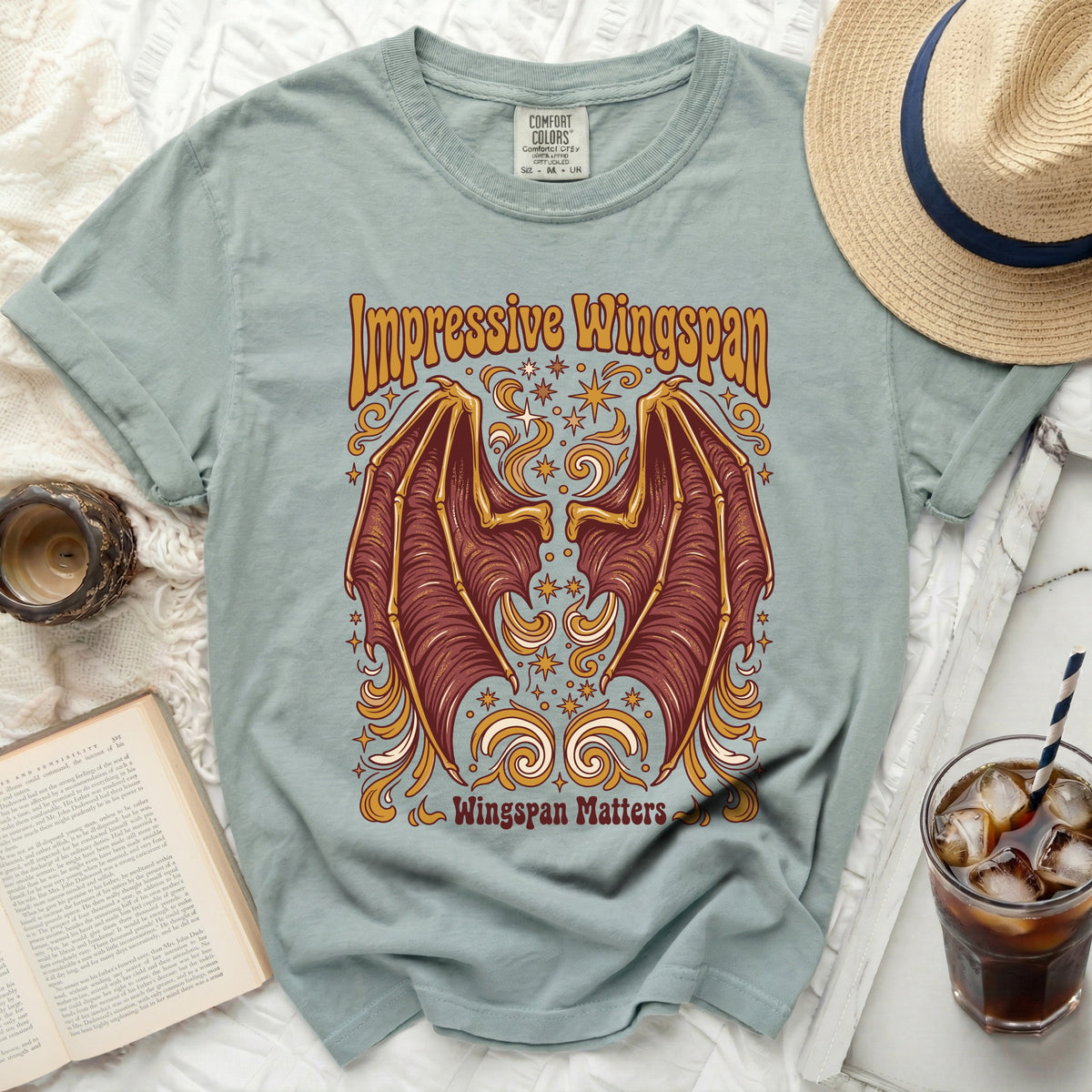 Green t-shirt with graphic of red dragon wings, stars, and text "Impressive Wingspan Wingspan Matters".