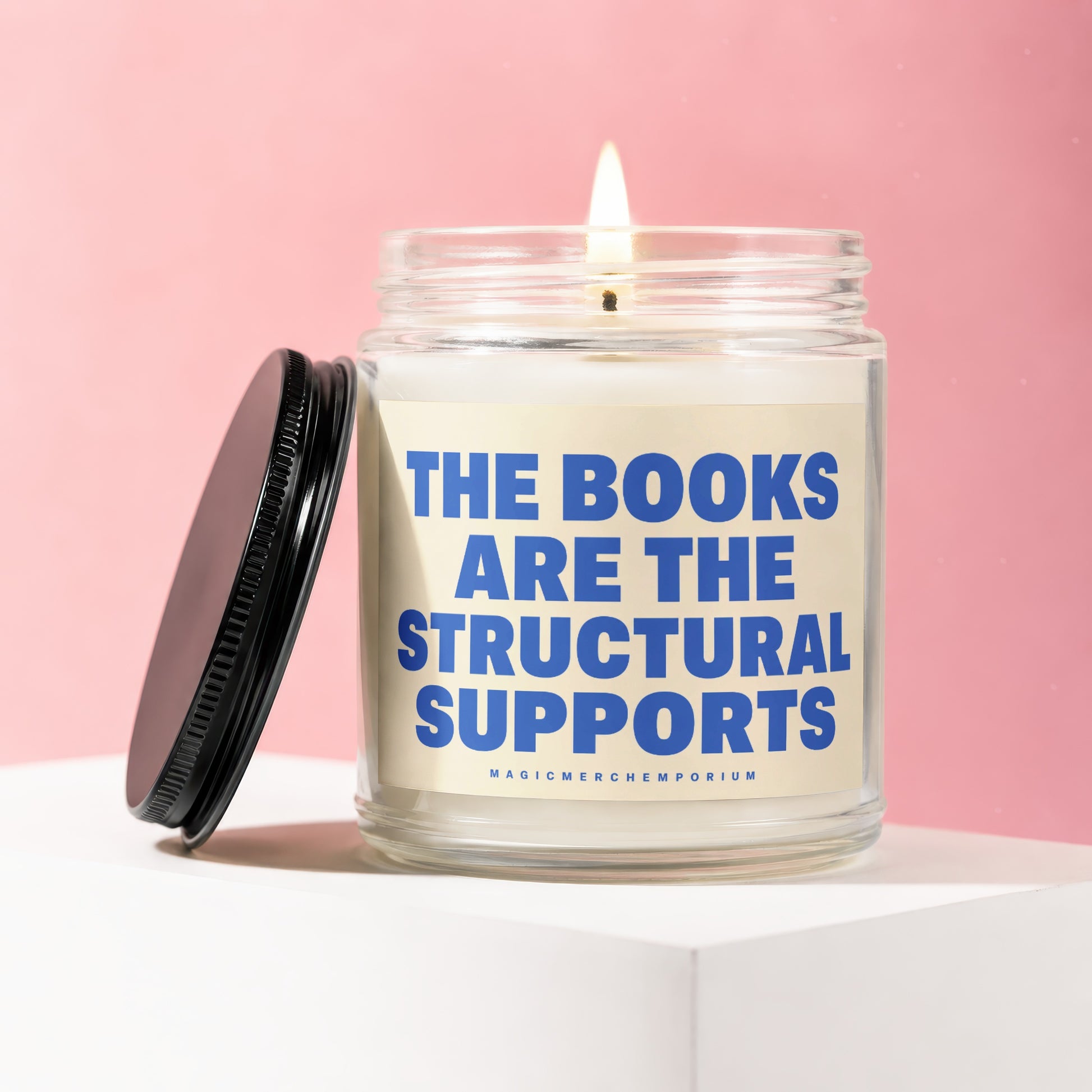 Candle with text "THE BOOKS ARE THE STRUCTURAL SUPPORTS" on a pink background.