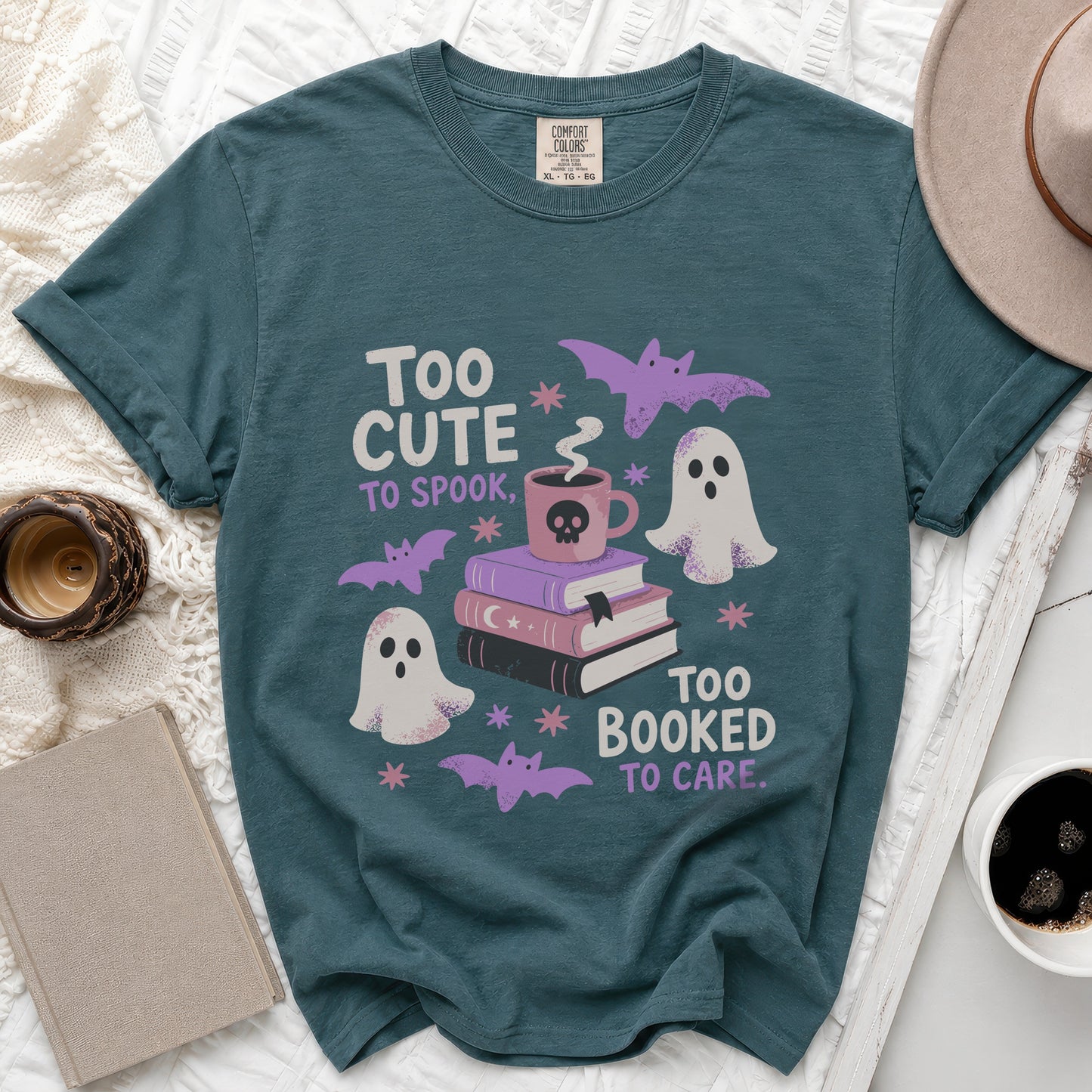 Teal t-shirt with "Too cute to spook, too booked to care" Halloween graphic.