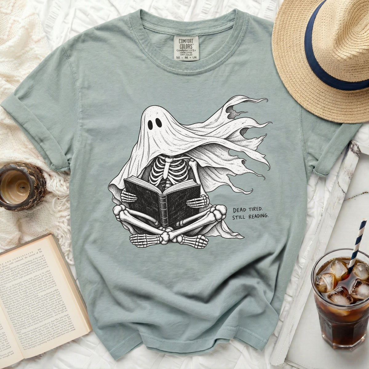 T-shirt with skeleton ghost reading a book, text says "Dead Tired. Still Reading."
