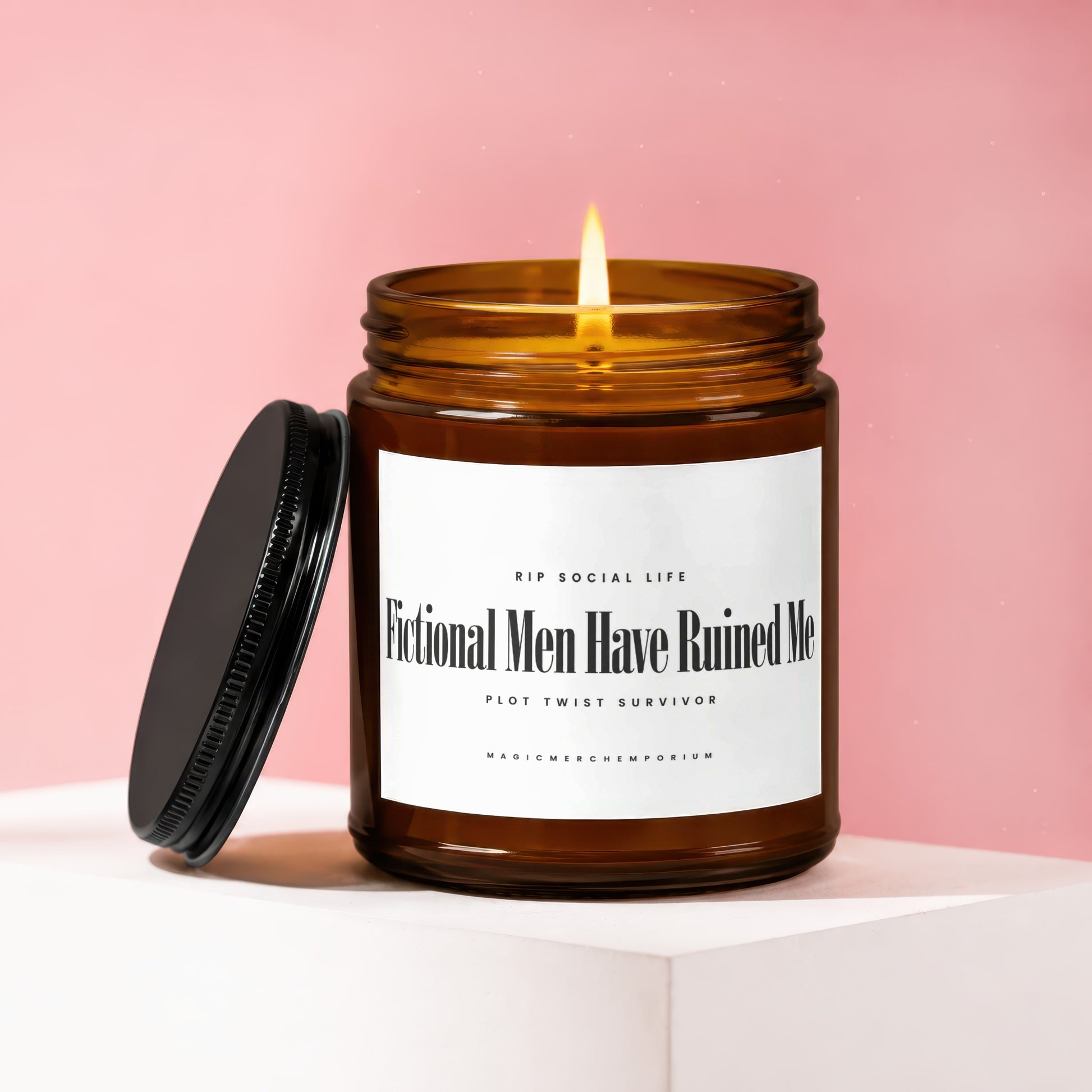 Amber glass candle with lit wick, black lid, and label text "Fictional Men Have Ruined Me."