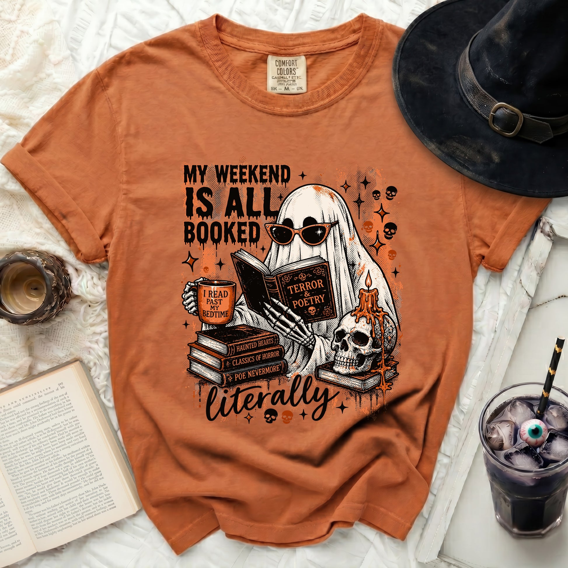 Orange t-shirt graphic features a ghost reading with books, skulls, and text.