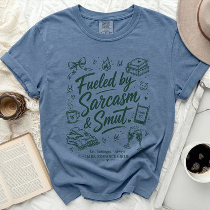 Blue Comfort Colors t-shirt with "Fueled by Sarcasm & Smut" text and icons.