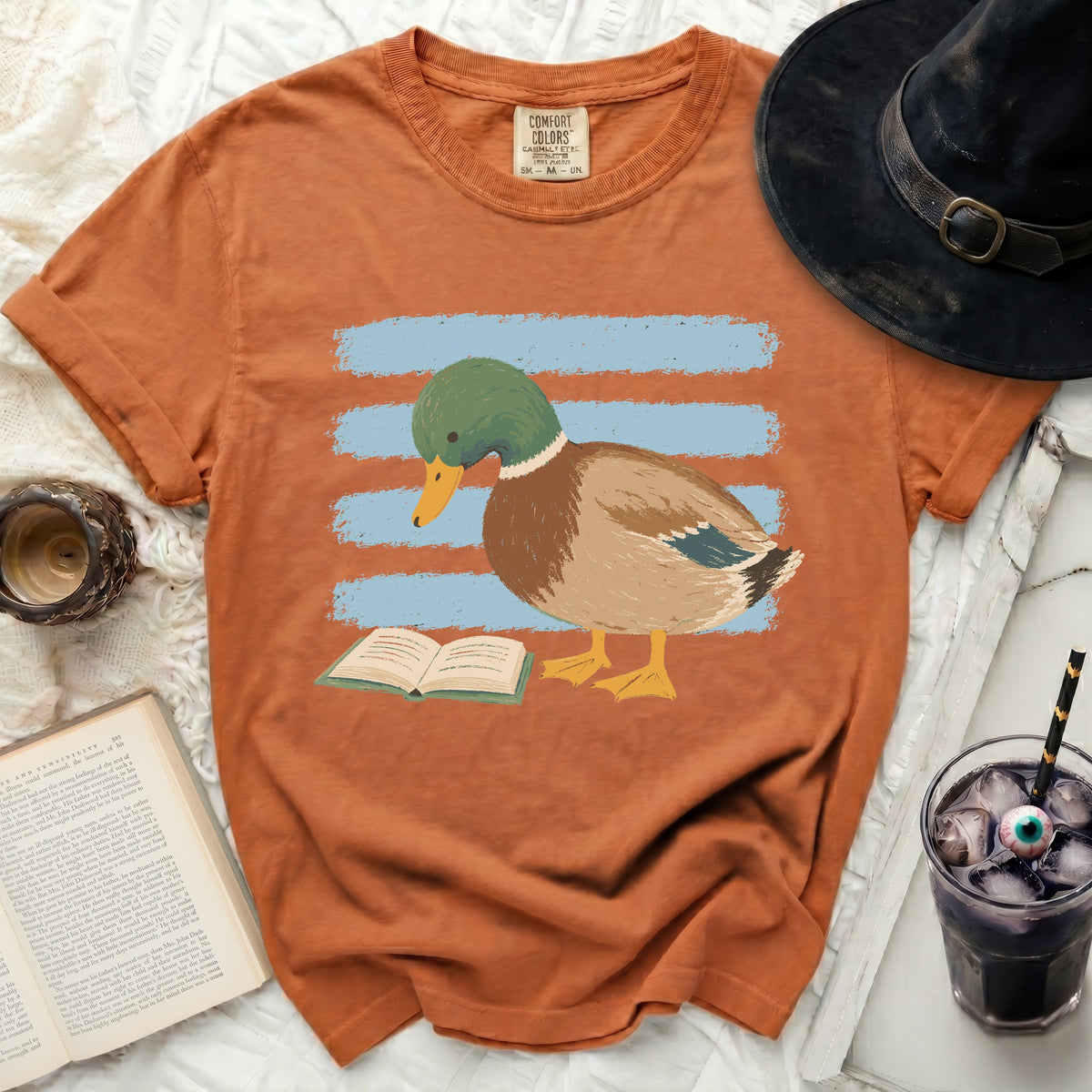 Orange t-shirt with a graphic of a mallard duck reading a book.