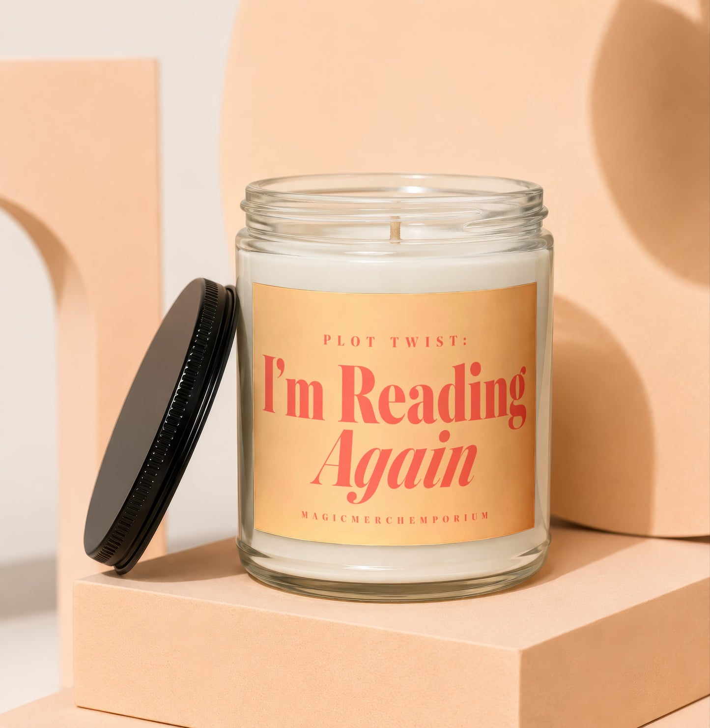 Glass candle with black lid and peach label that reads "I'm Reading Again".