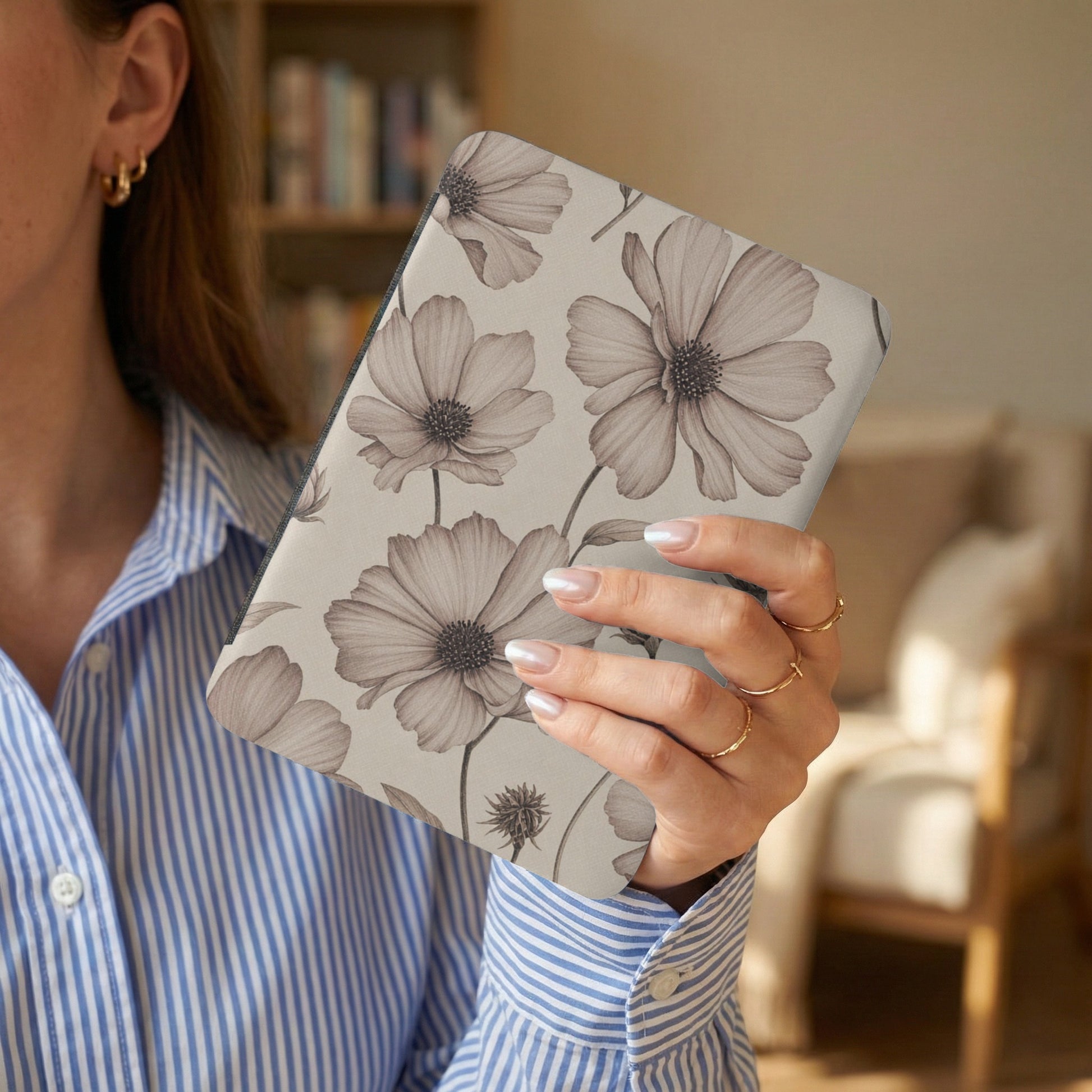 Woman holding a tablet with a neutral floral pattern.