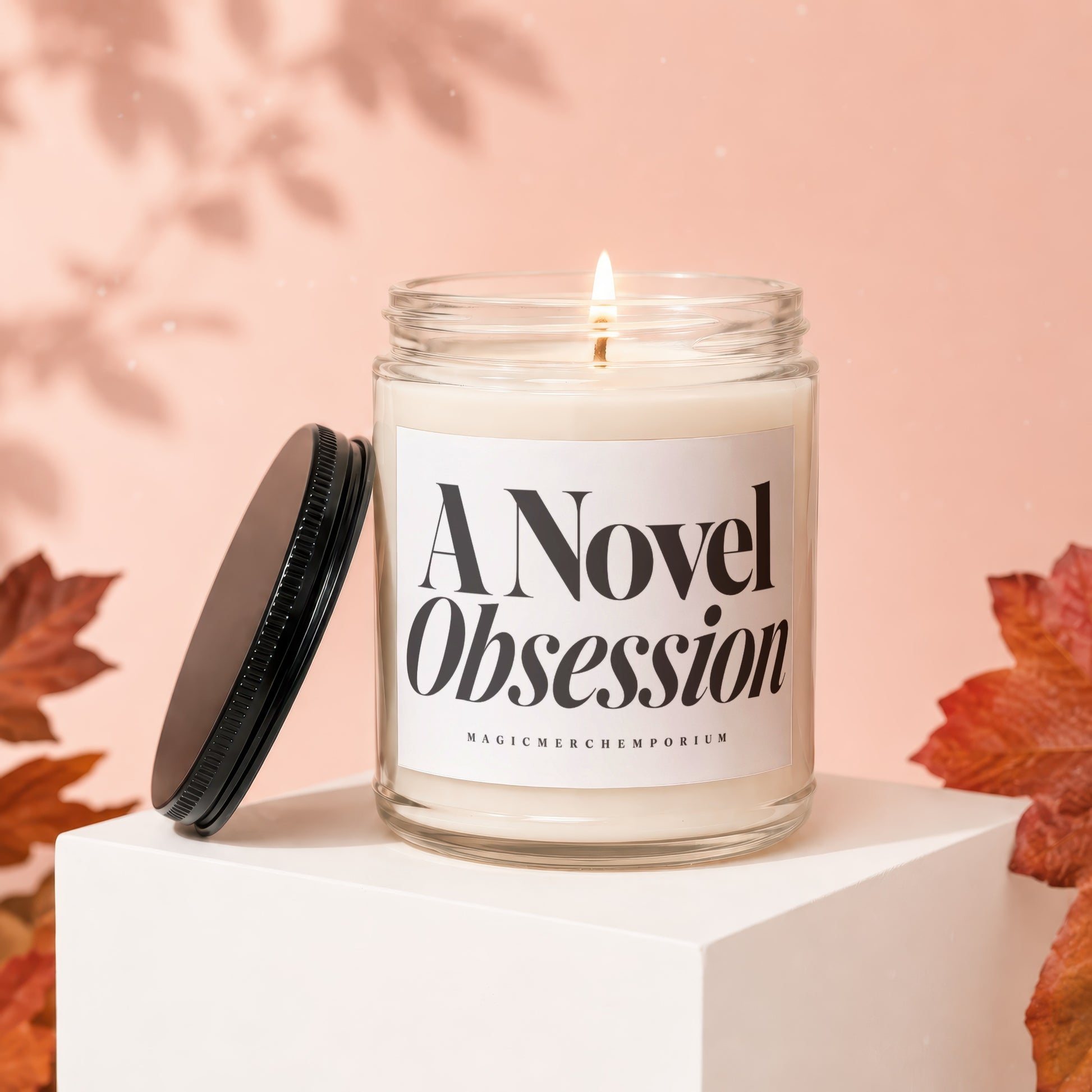 Glass candle with lit wick, black lid, and "A Novel Obsession" label.