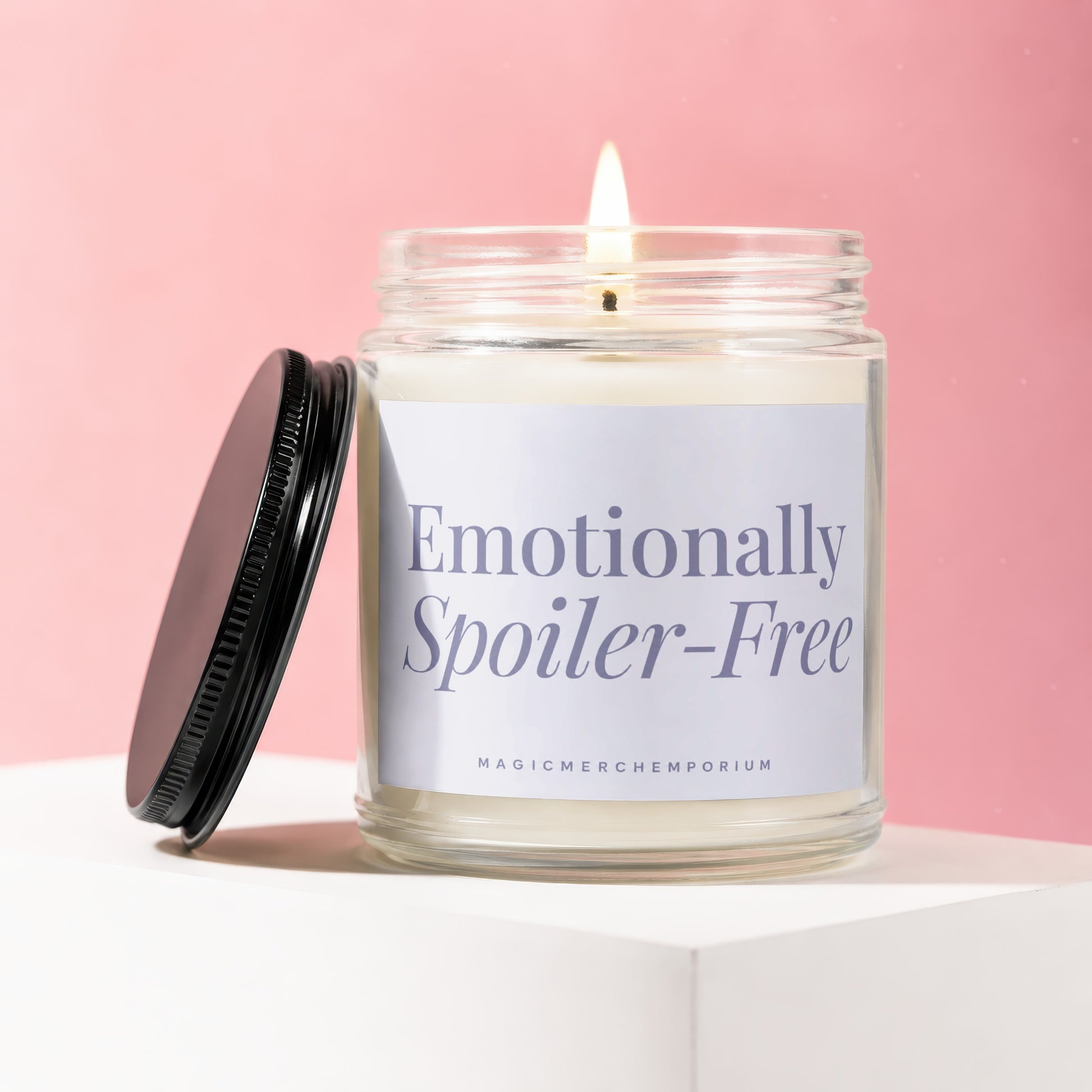 Lit candle in glass jar with black lid, label reads "Emotionally Spoiler-Free".