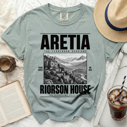 Light green t-shirt with black text "ARETIA", "RIORSON HOUSE", "FROM ASHES", and "WE RISE".