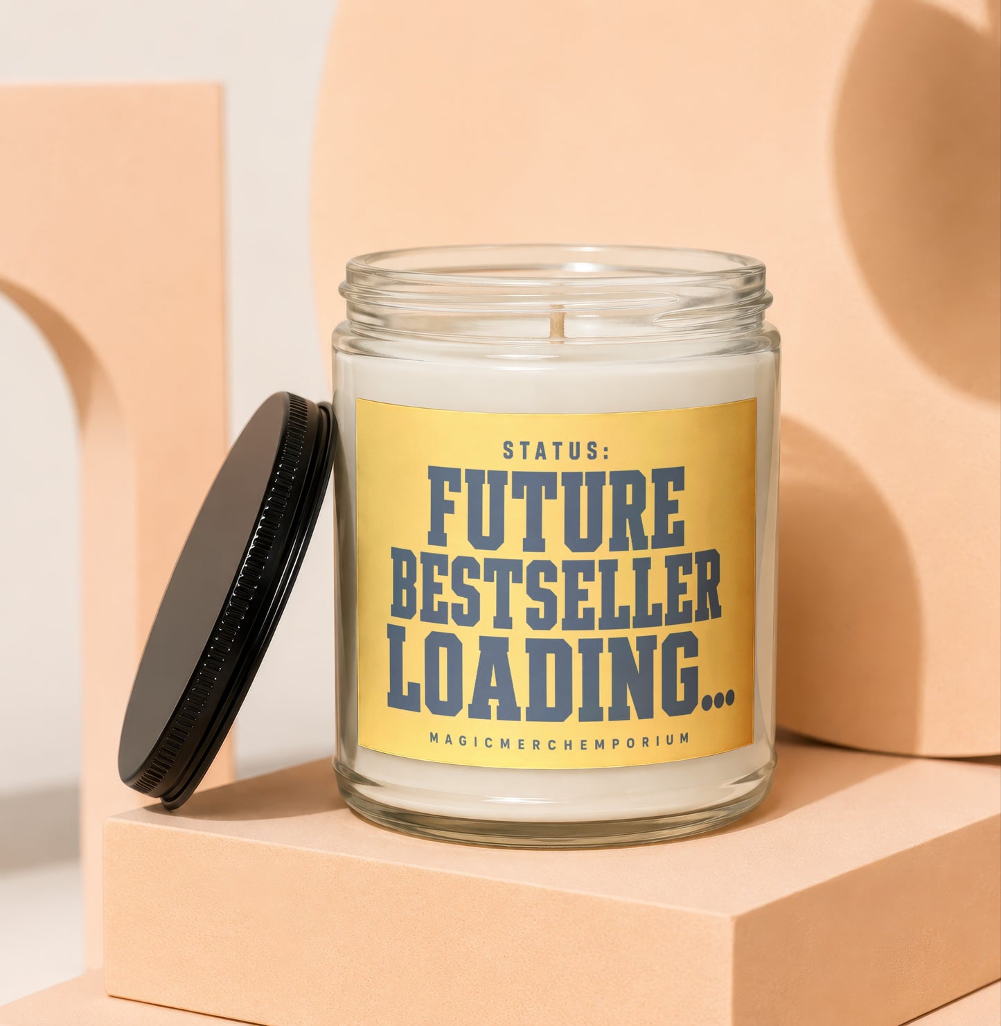 Glass candle with yellow label reading "STATUS: FUTURE BESTSELLER LOADING..."