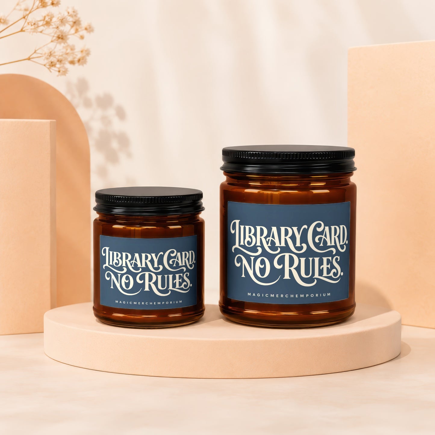 Two amber glass candles with black lids, featuring "Library Card. No Rules." text.