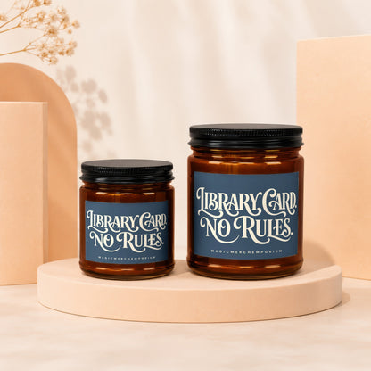 Two amber glass candles with black lids, featuring "Library Card. No Rules." text.