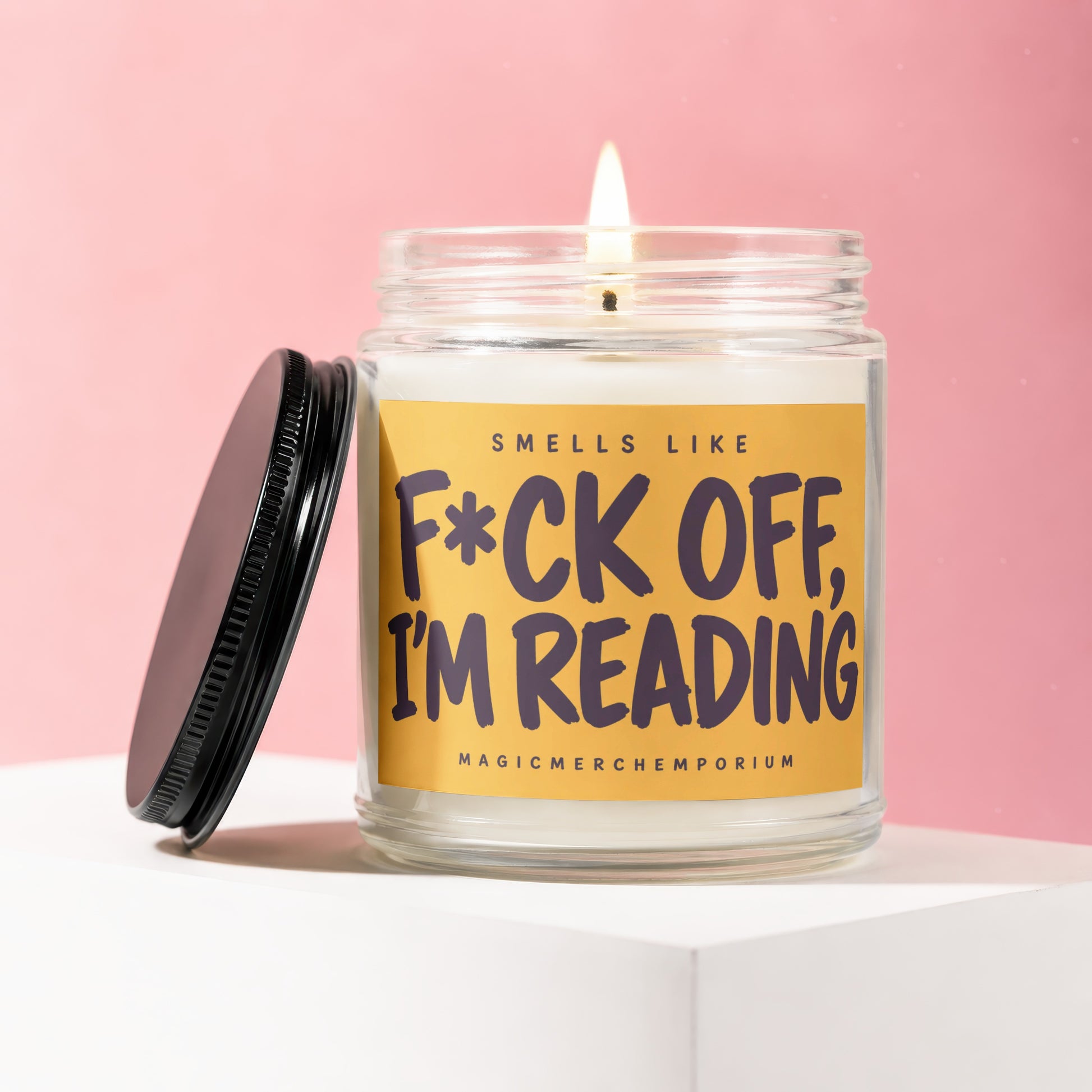 Candle with text "Smells Like F*ck Off, I'm Reading" on a yellow label.