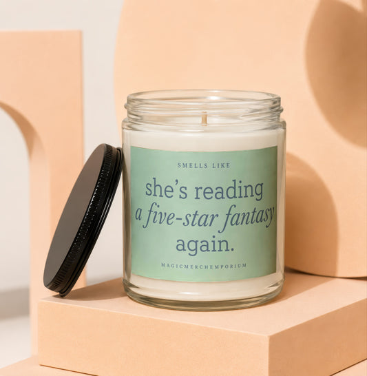 Glass candle with black lid, featuring a label that reads "SMELLS LIKE she's reading a five-star fantasy again."