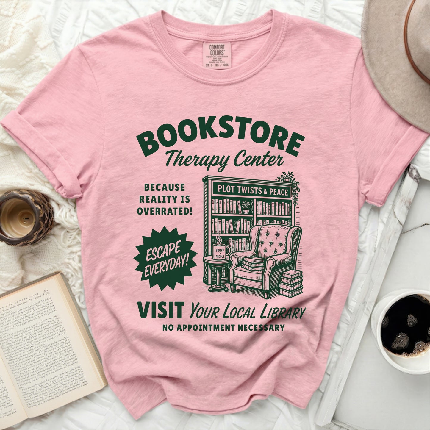 Pink t-shirt with "Bookstore Therapy Center" graphic of armchair and bookshelf.