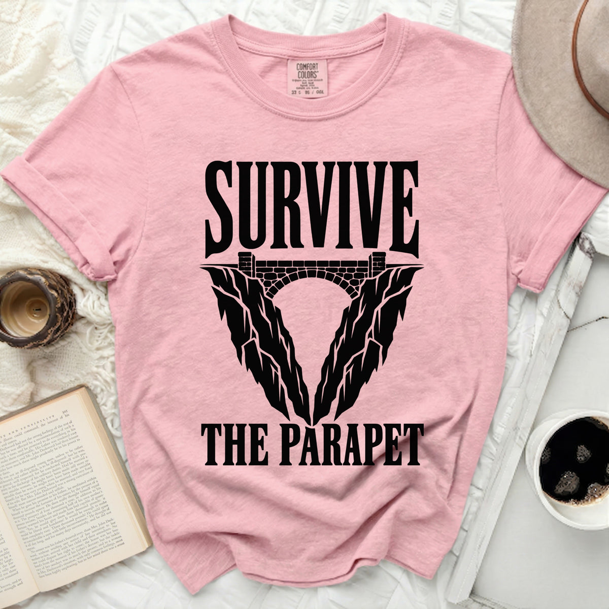 Pink t-shirt with black text and graphic saying "SURVIVE THE PARAPET".