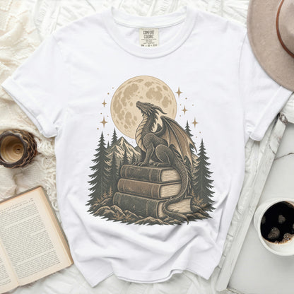 White t-shirt with a dragon sitting on books under a full moon.