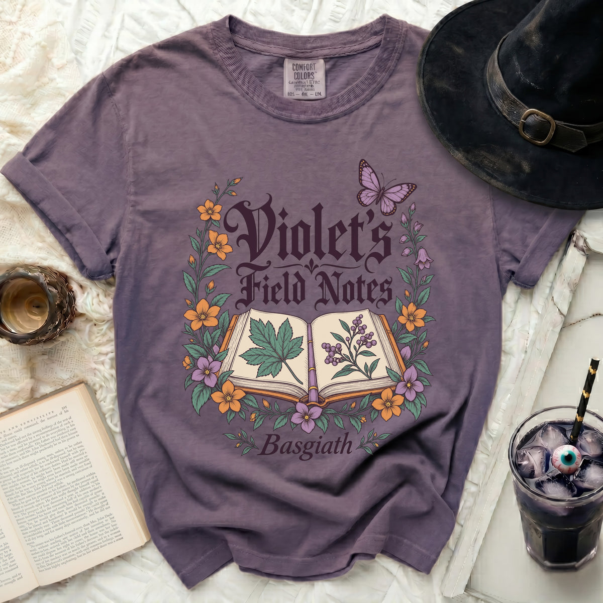 Purple t-shirt with "Violet's Field Notes Basgiath" text and botanical illustration.