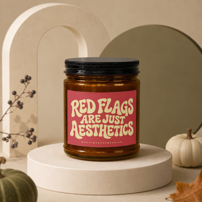 Amber candle with black lid and red label reading "Red Flags Are Just Aesthetics".