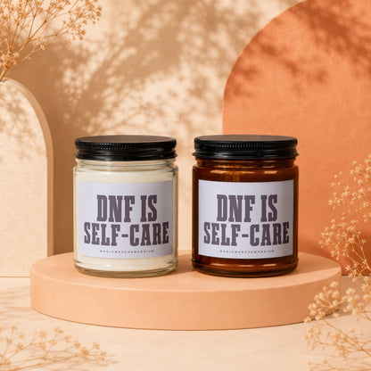 Two glass candles with black lids, one clear and one amber, labeled "DNF IS SELF-CARE".