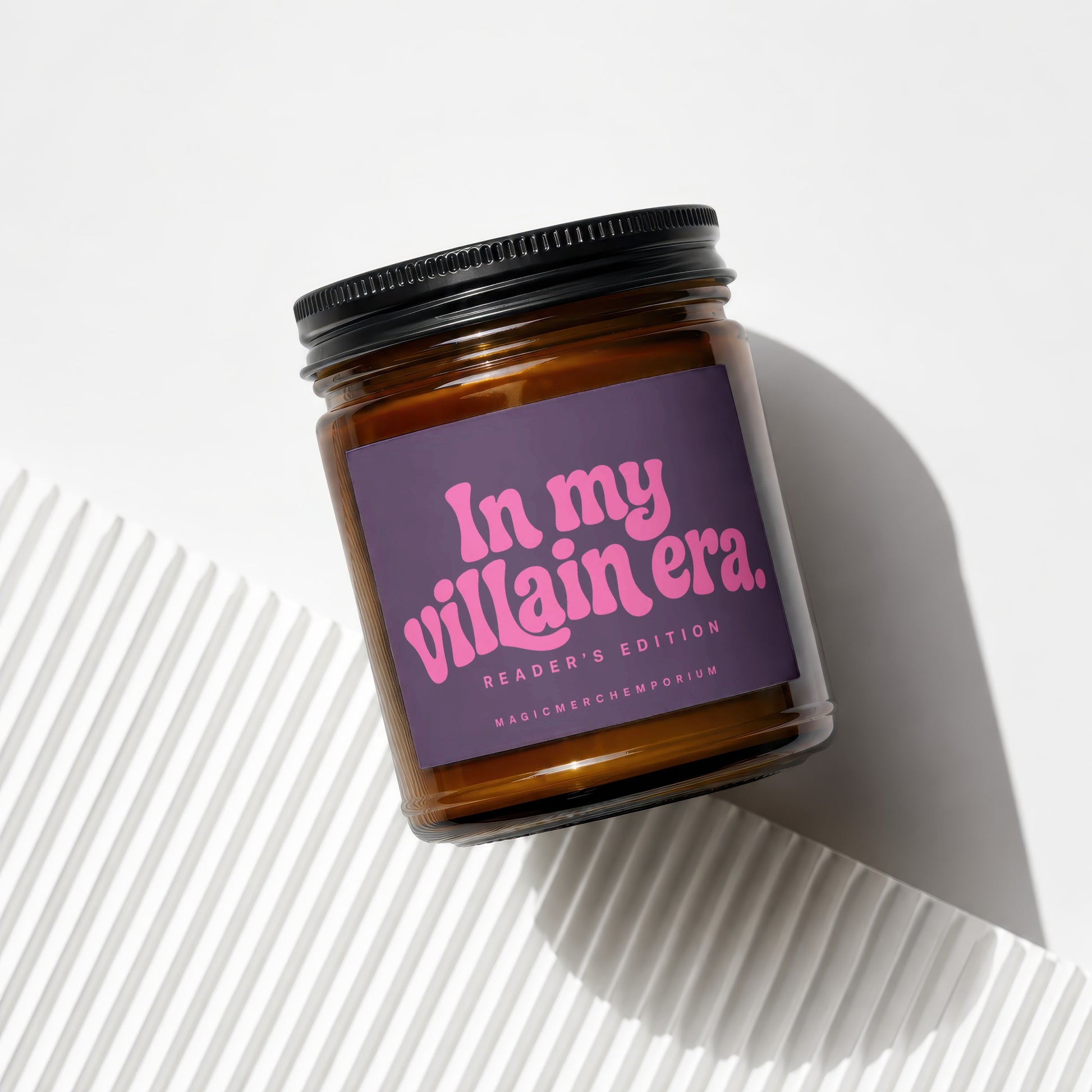 Amber glass candle with purple label reading "In my villain era. Reader's Edition."