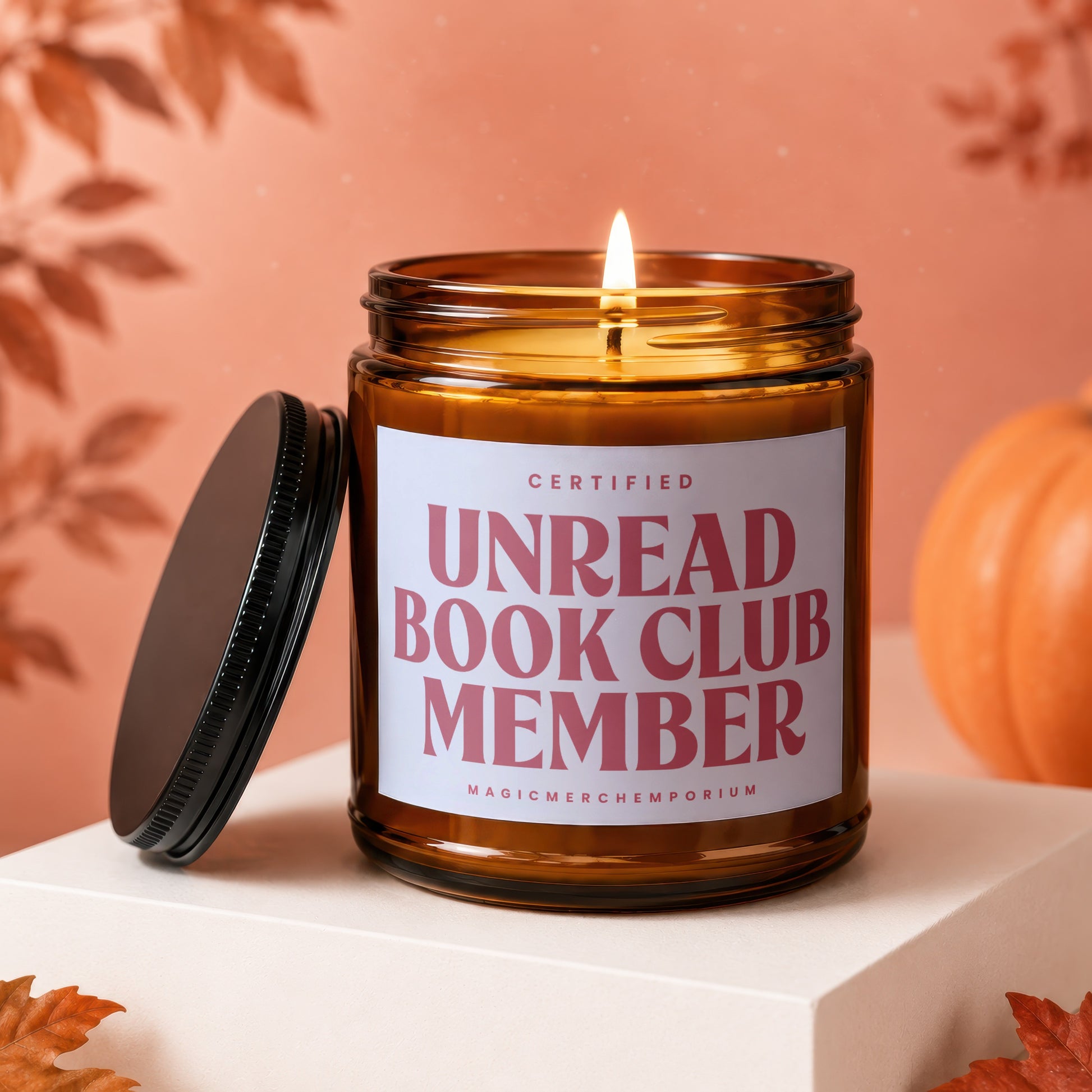 Brown glass candle with lit wick reads "Certified Unread Book Club Member".