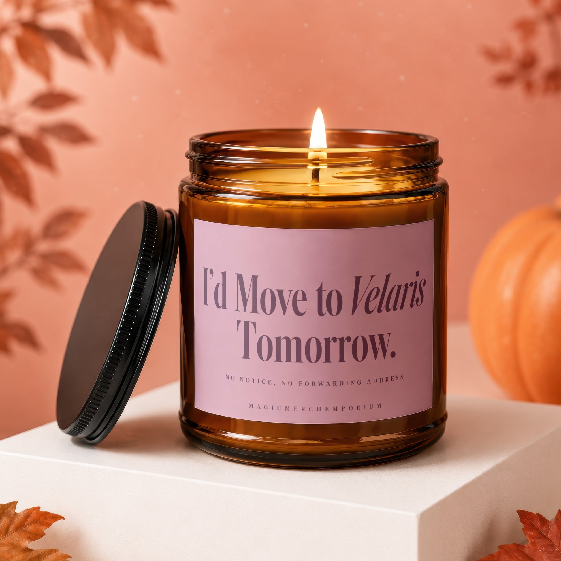 An amber glass jar candle with a lit wick, black lid, and a pink label reading "I'd Move to Velaris Tomorrow."