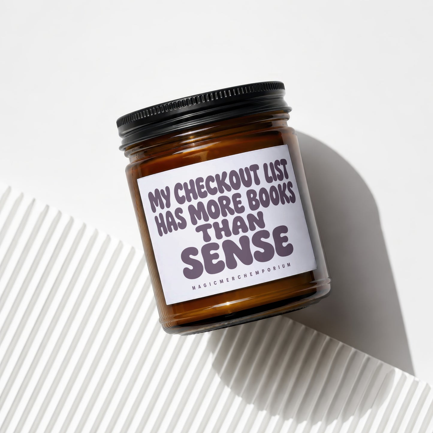Amber jar candle with "My checkout list has more books than sense" text.